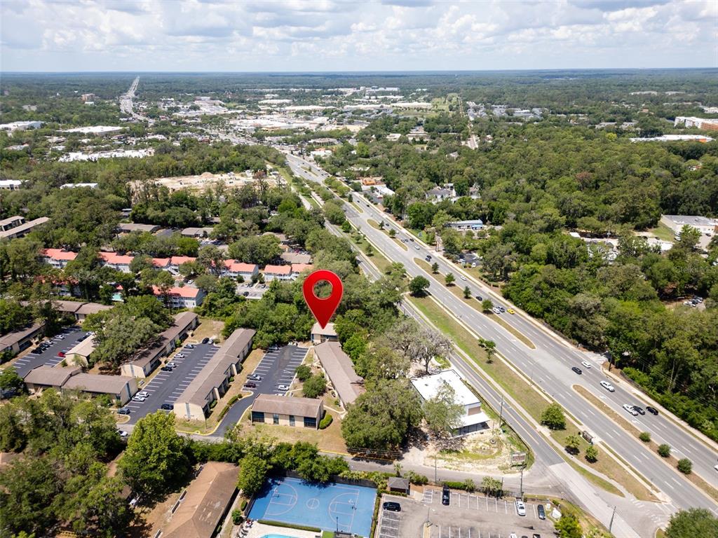 An aerial view shows a multi-family residential complex with a basketball court and parking lots — 2811 SW ARCHER ROAD UNIT C18, GAINESVILLE, FL