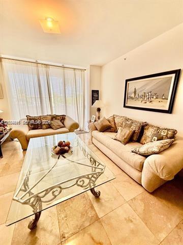 A living room features a glass coffee table, two beige sofas, and tile flooring — 9595 Collins Ave # G, Surfside FL 33154, SURFSIDE, FL