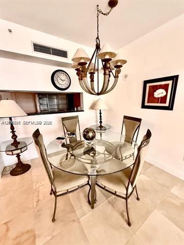 A dining area features a glass-topped table, four chairs, and a decorative chandelier — 9595 Collins Ave # G, Surfside FL 33154, SURFSIDE, FL