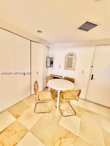 A dining area features a round white table, three cane chairs, and marble tile flooring — 9595 Collins Ave # G, Surfside FL 33154, SURFSIDE, FL