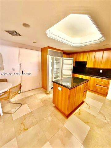 A kitchen with wood cabinets, a granite-topped island, and a large skylight above — 9595 Collins Ave # G, Surfside FL 33154, SURFSIDE, FL