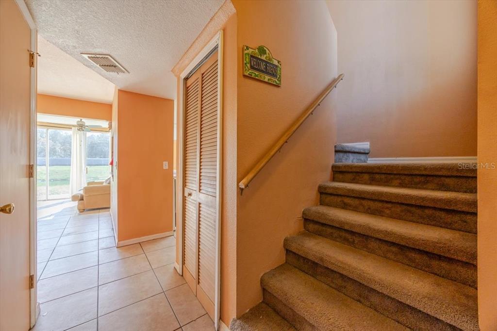 An interior view shows a carpeted staircase next to a closet and a tiled hallway — 203 COCO PLUM DRIVE Main Unit, DAVENPORT, FL
