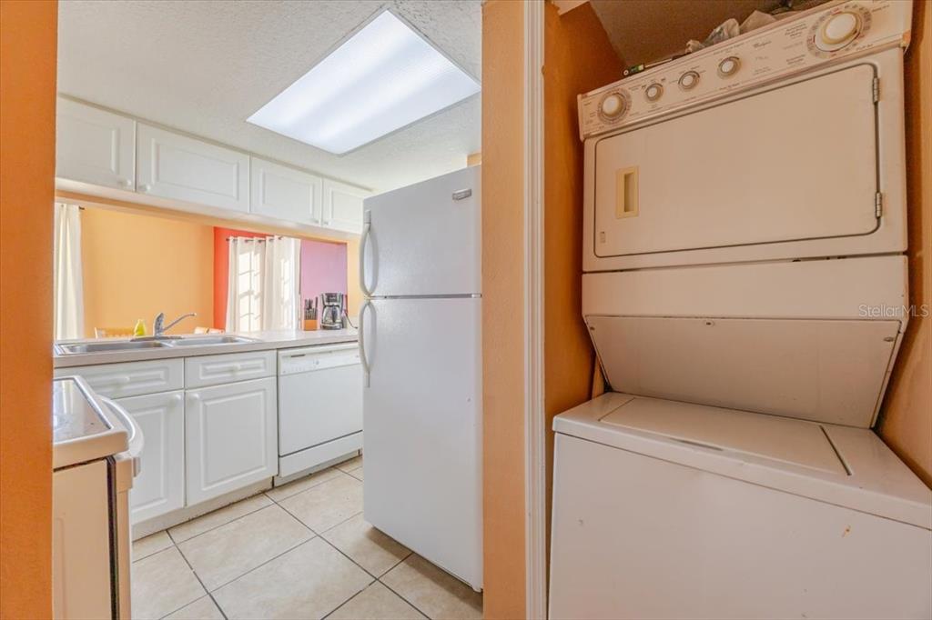 A kitchen with white cabinets and a stacked washer and dryer in the foreground — 203 COCO PLUM DRIVE Main Unit, DAVENPORT, FL