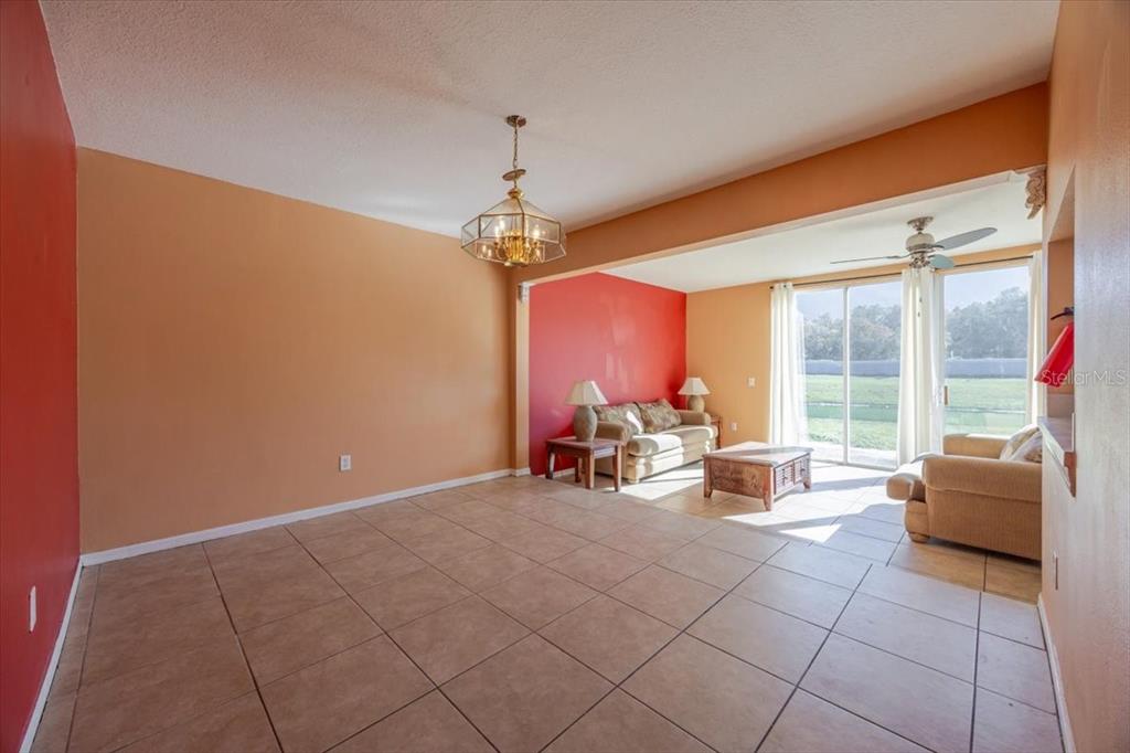 A living and dining area features tile floors, a chandelier, and a sliding glass door — 203 COCO PLUM DRIVE Main Unit, DAVENPORT, FL