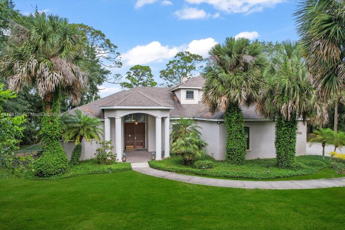 A single-story house with a columned entryway, surrounded by palm trees and a green lawn — 6340 US 1, Cocoa FL 32927, COCOA, FL