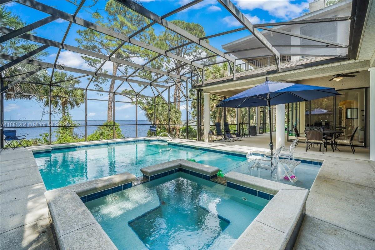 A screened-in pool and hot tub overlook a lake from a covered patio — 6340 US 1, Cocoa FL 32927, COCOA, FL