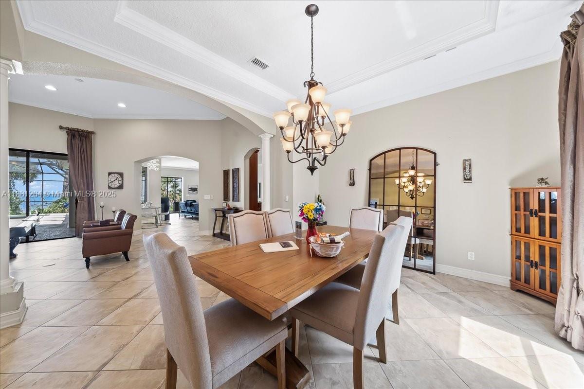A dining room with a wooden table, chandelier, and arched mirror in an open-concept home — 6340 US 1, Cocoa FL 32927, COCOA, FL
