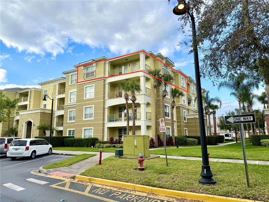 The exterior of a multi-story apartment building features a highlighted top-floor balcony — 5049 SHOREWAY LOOP UNIT 407, ORLANDO, FL