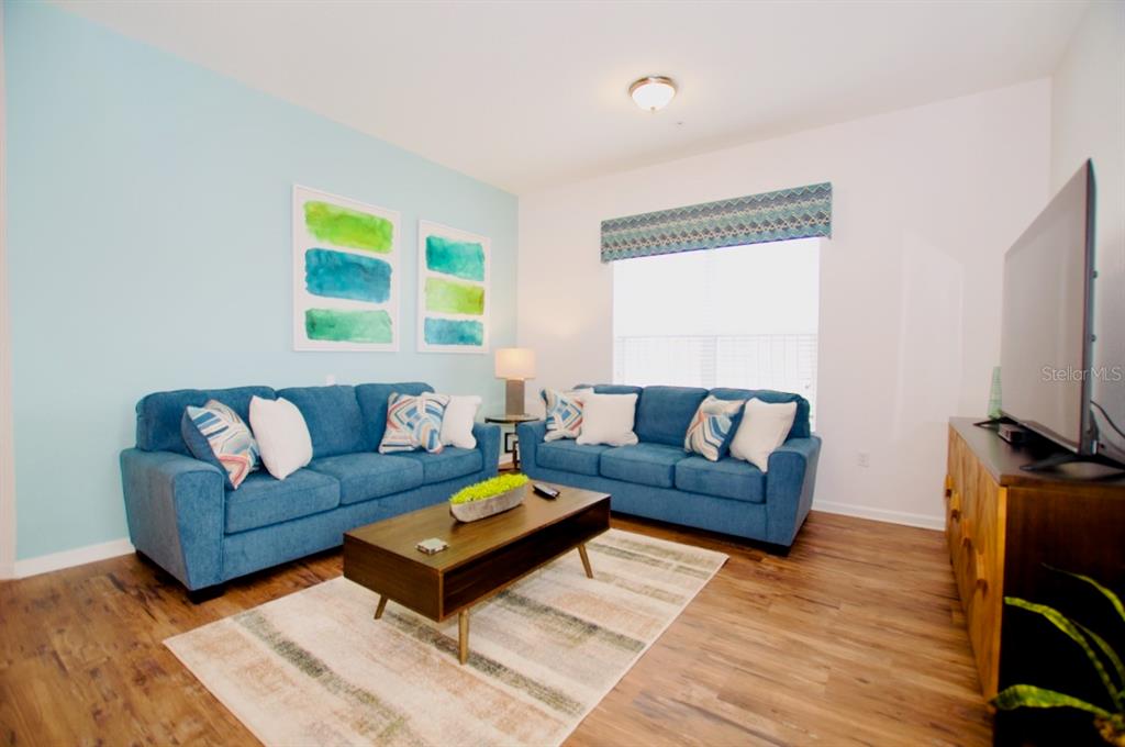 A living room features two blue sofas, a coffee table, and a light blue wall — 5049 SHOREWAY LOOP UNIT 407, ORLANDO, FL