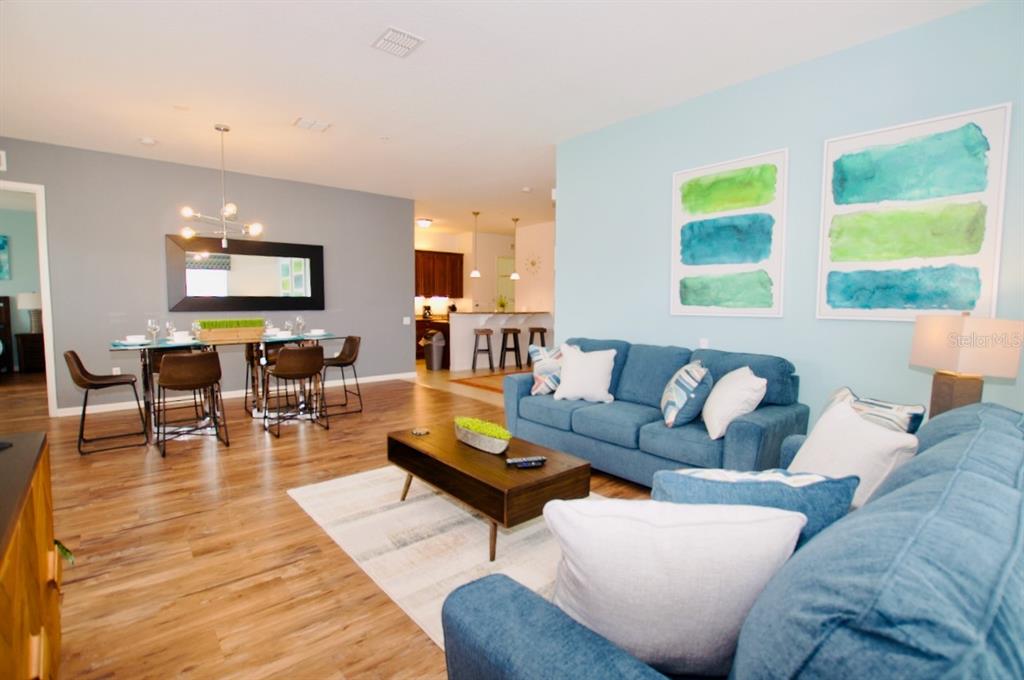 An open-concept living and dining area features blue walls, wood flooring, and blue sofas — 5049 SHOREWAY LOOP UNIT 407, ORLANDO, FL