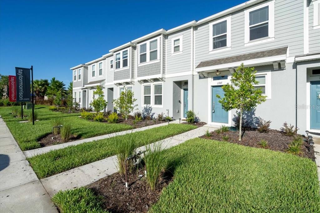 A row of modern two-story townhomes with light gray siding and blue front doors — 11747 STONESMITH CROSSING, PALMETTO, FL