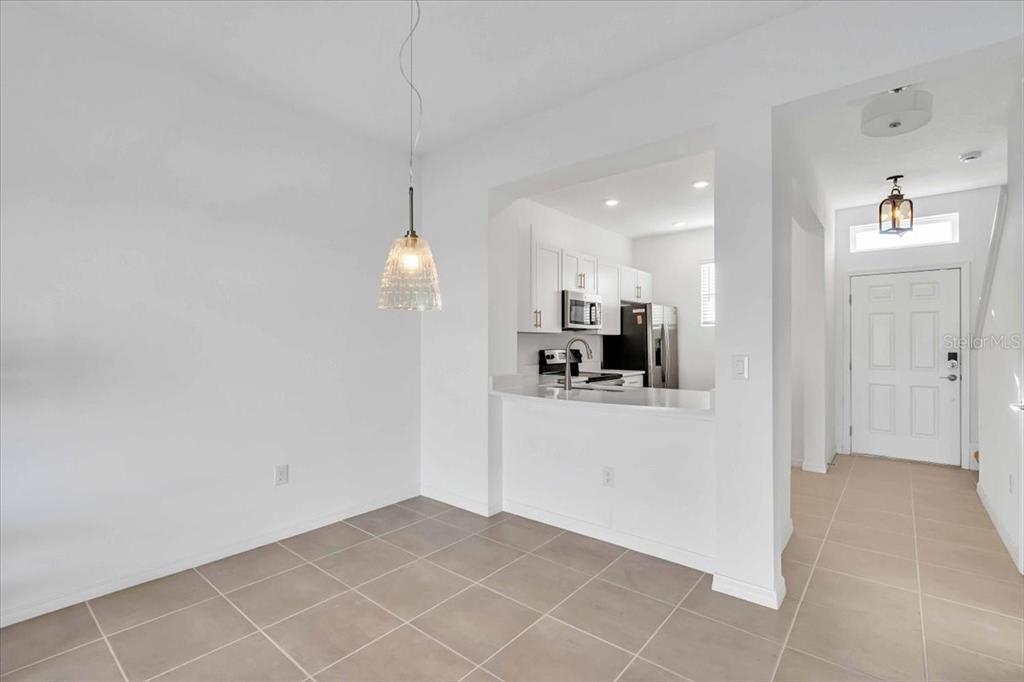 A dining area with tile flooring opens to a kitchen with white cabinets and appliances — 11747 STONESMITH CROSSING, PALMETTO, FL