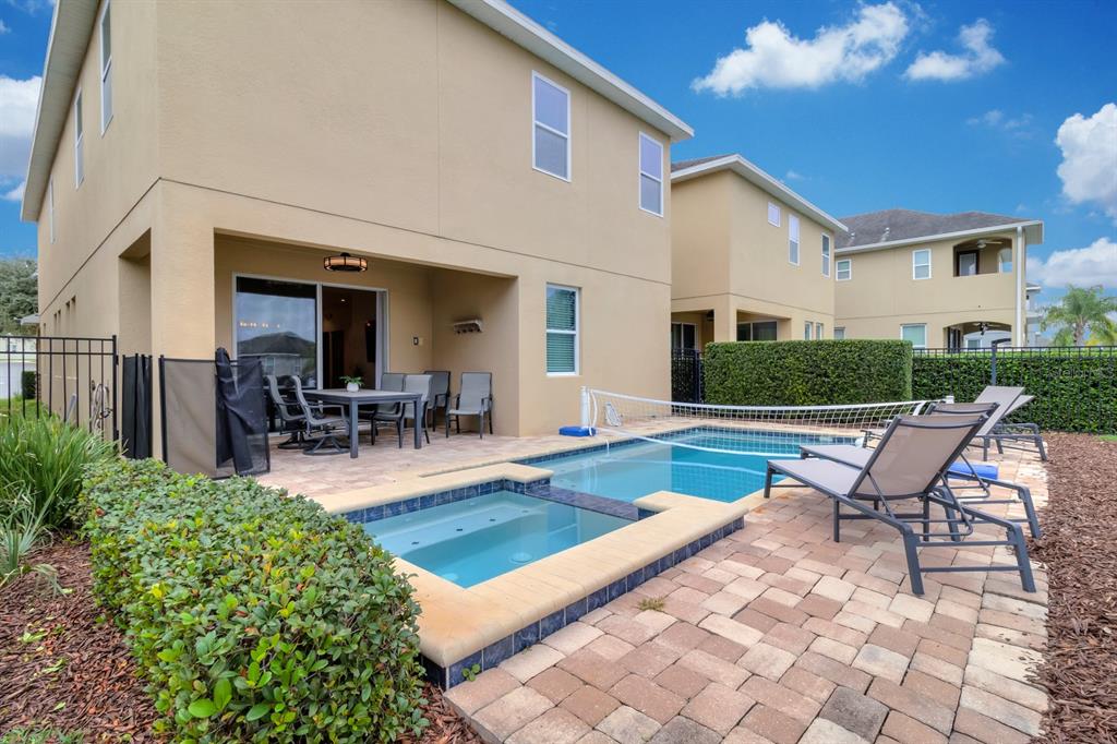 A two-story house with a patio, swimming pool, spa, and lounge chairs in the backyard — 7568 MARKER AVENUE, KISSIMMEE, FL