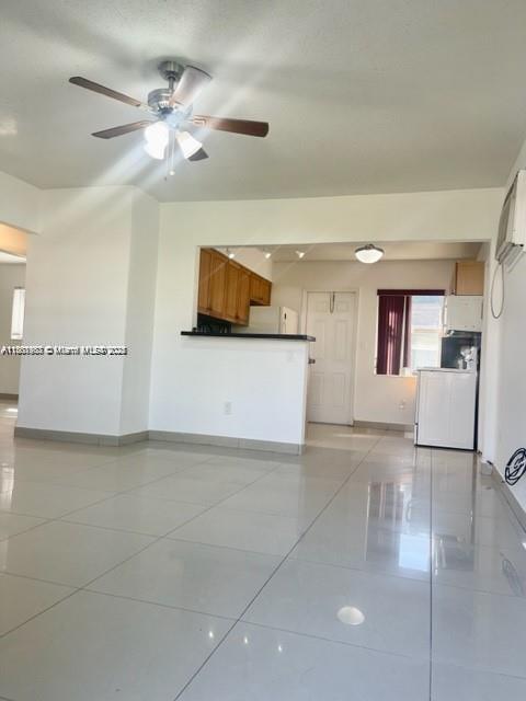 A bright living room with white tile floors leads to an open kitchen with wooden cabinets — 310 SW 10th Ter, Hallandale Beach FL 33009, HALLANDALE BEACH, FL