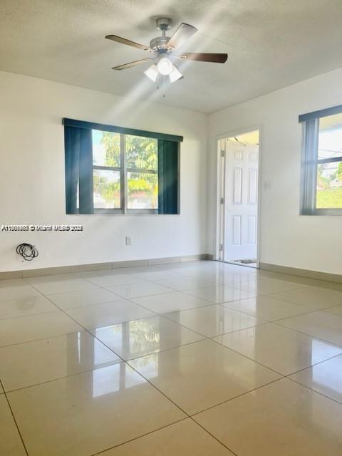 An empty room features light-colored tile flooring, a ceiling fan, and a white door — 310 SW 10th Ter, Hallandale Beach FL 33009, HALLANDALE BEACH, FL