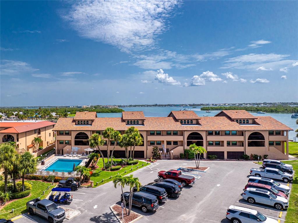 An aerial view shows a multi-story apartment building with a pool and parking lot — 1765 GULF BOULEVARD UNIT 203, ENGLEWOOD, FL