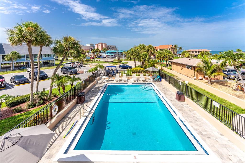 An elevated view of a rectangular swimming pool surrounded by a patio and black fencing — 1765 GULF BOULEVARD UNIT 203, ENGLEWOOD, FL