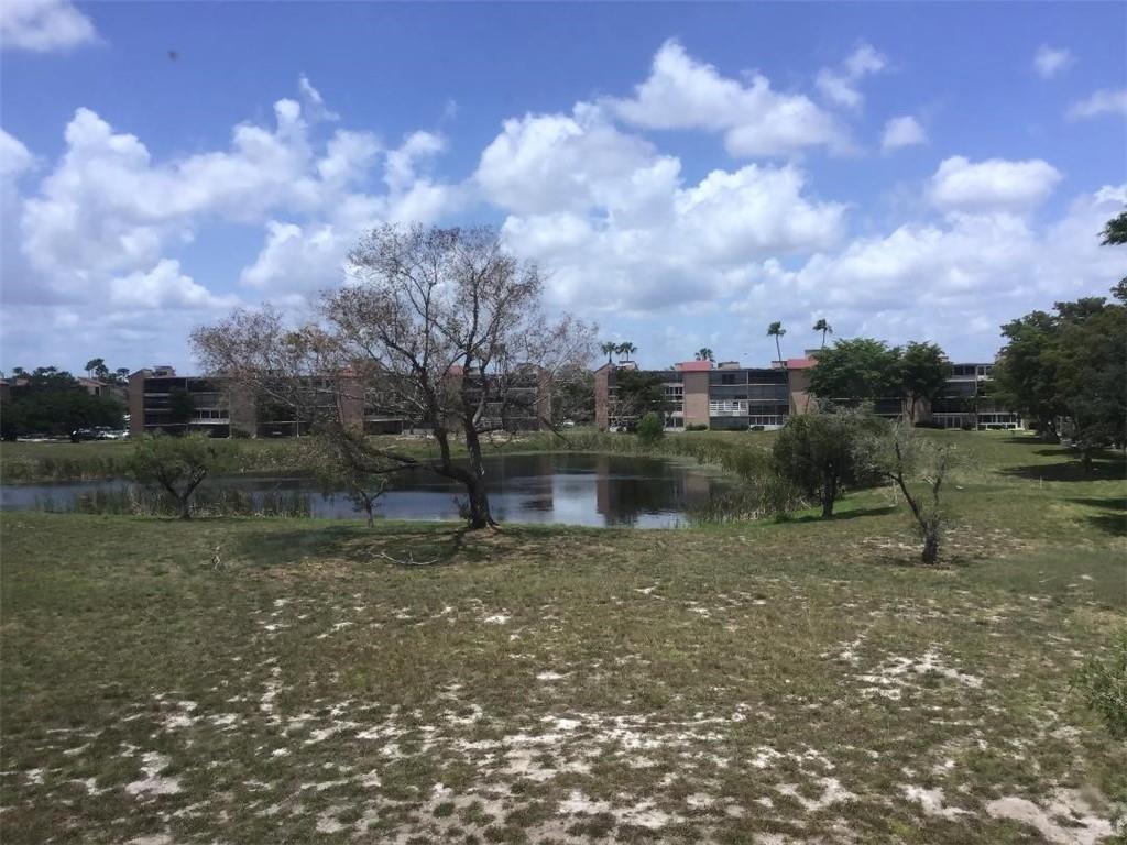 A pond sits in front of multi-story apartment buildings under a blue, cloudy sky — 7301 NW 1st Street # 406, Margate FL 33063, MARGATE, FL