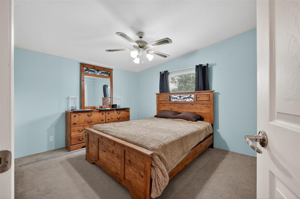 A bedroom features light blue walls, a wooden bed frame, a matching dresser, and carpet — 163 WEST STREET, OAK HILL, FL