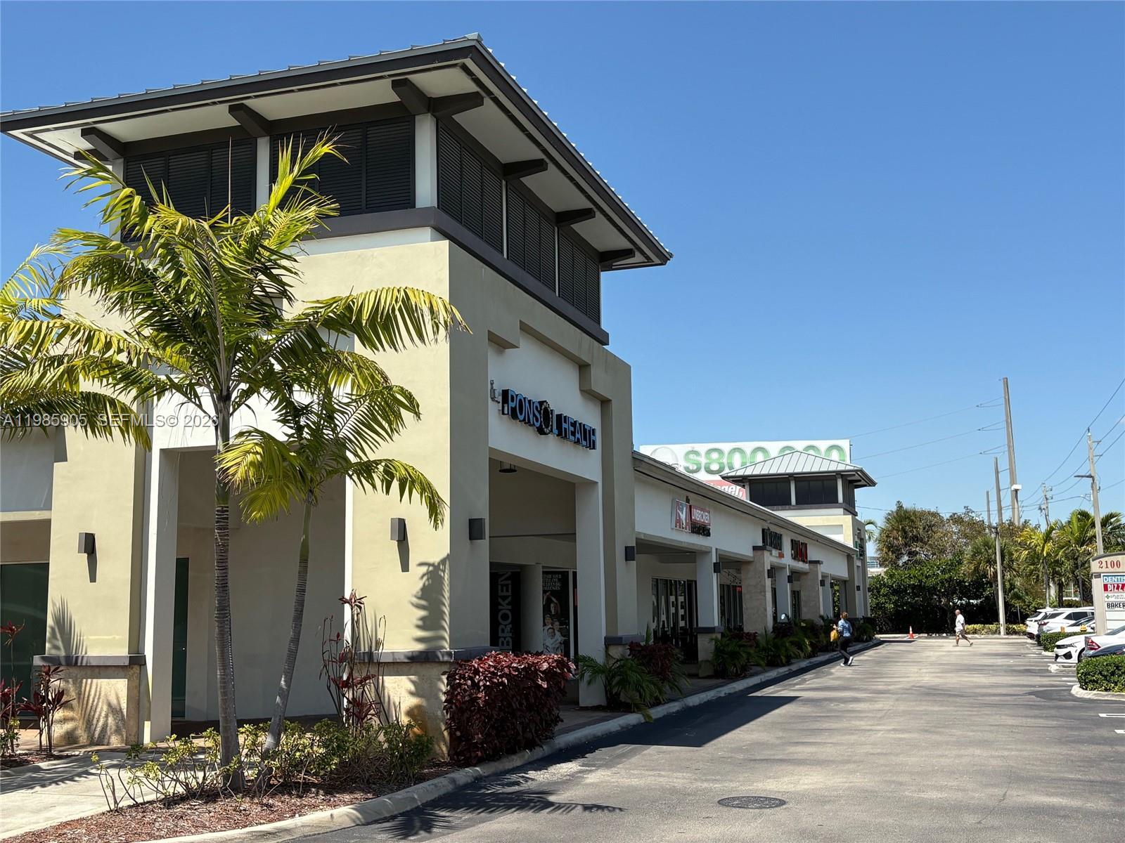 A low-angle exterior view of a commercial strip mall with a palm tree in front — 2100 NW 107th Ave, Doral FL 33172, DORAL, FL