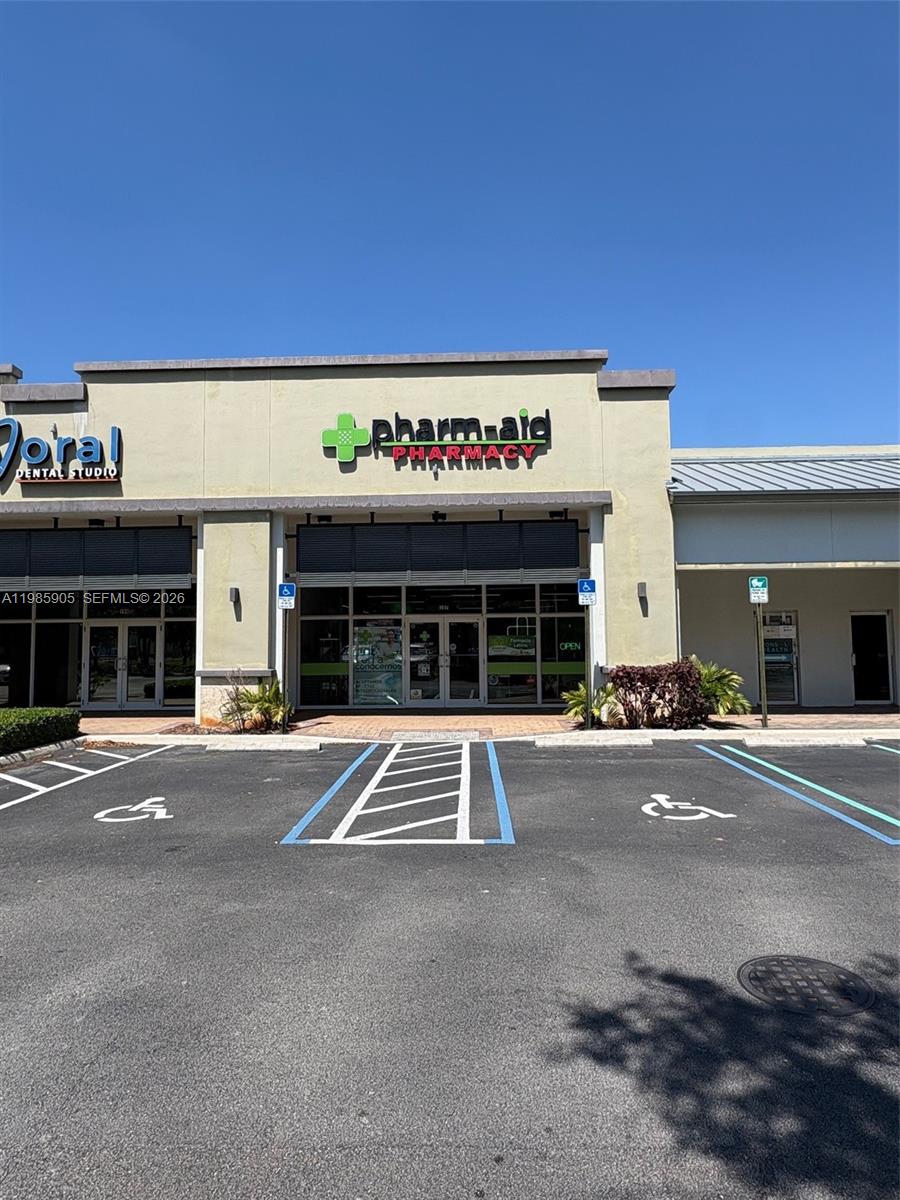 The exterior of a commercial building features a pharmacy storefront with two designated handicap parking spaces — 2100 NW 107th Ave, Doral FL 33172, DORAL, FL