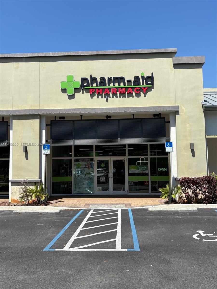 The exterior of a Pharm-Aid pharmacy storefront features a sign and a handicap parking space — 2100 NW 107th Ave, Doral FL 33172, DORAL, FL