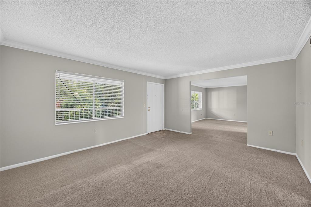 An empty living room features beige carpet, light gray walls, and a white front door — 128 WATER FRONT WAY UNIT 360, ALTAMONTE SPRINGS, FL