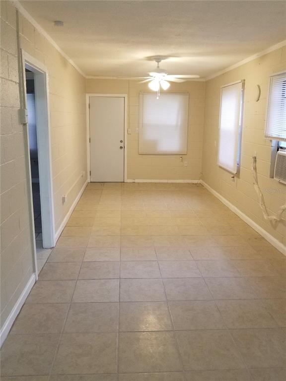 A room with beige tile flooring, light-colored block walls, a ceiling fan, and two windows — 1809 SW 3RD STREET, OCALA, FL