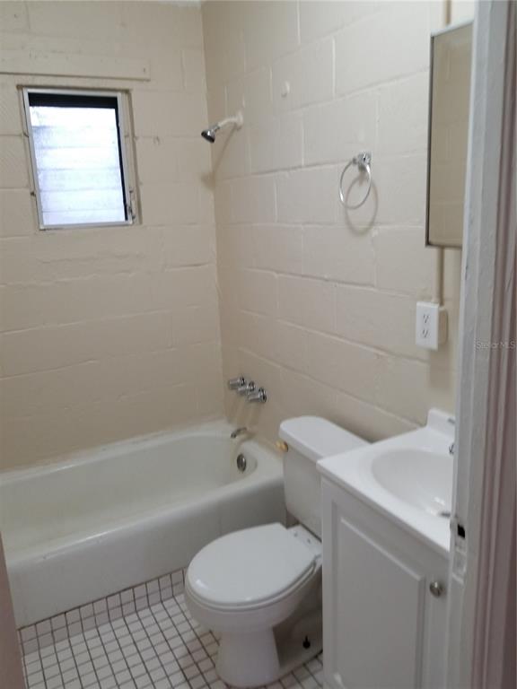 A bathroom features a white tub, toilet, vanity, and a window against painted block walls — 1809 SW 3RD STREET, OCALA, FL