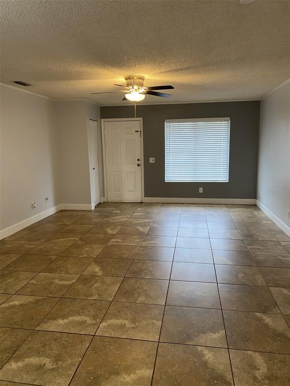 A living room with light gray walls, a dark accent wall, and tan tile flooring — 12310 TAVARES RIDGE COURT UNIT 144, TAVARES, FL