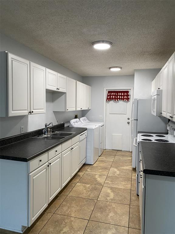 A kitchen features white cabinets, dark countertops, a sink, laundry appliances, and tile flooring — 12310 TAVARES RIDGE COURT UNIT 144, TAVARES, FL
