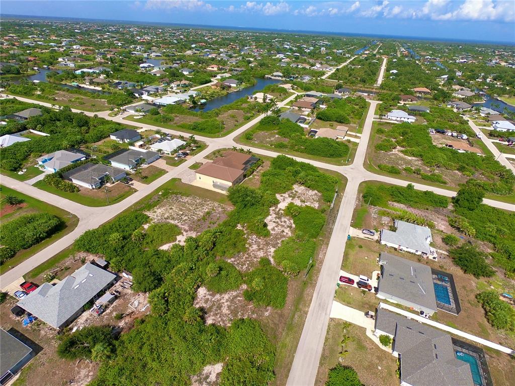 An aerial view shows a residential neighborhood with houses, paved roads, and undeveloped wooded lots — 14132 UNION HALL AVENUE, PORT CHARLOTTE, FL