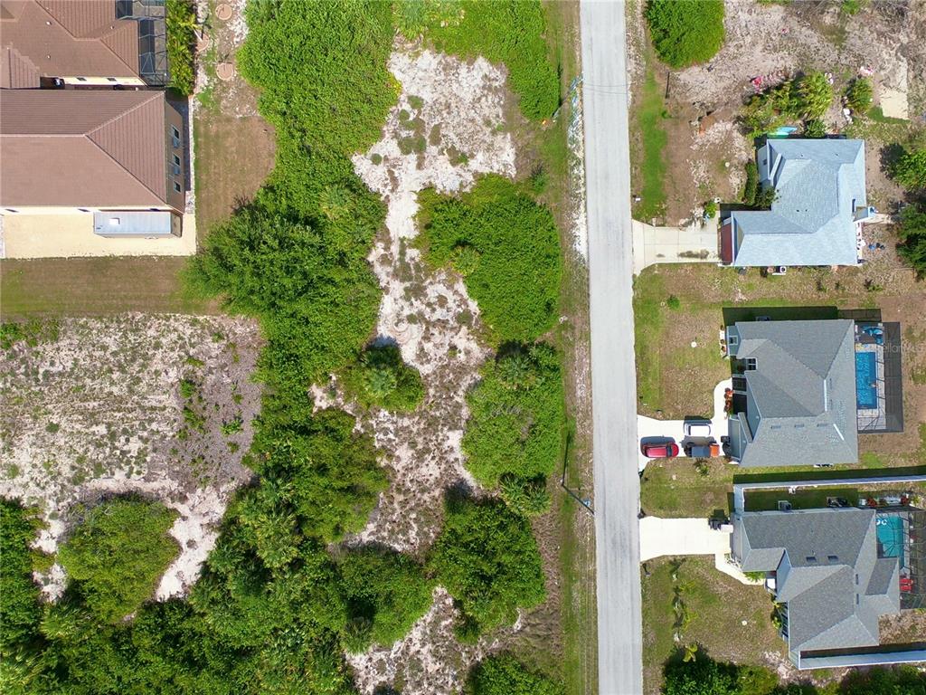 An aerial view shows a vacant, wooded lot situated between residential houses and a road — 14132 UNION HALL AVENUE, PORT CHARLOTTE, FL