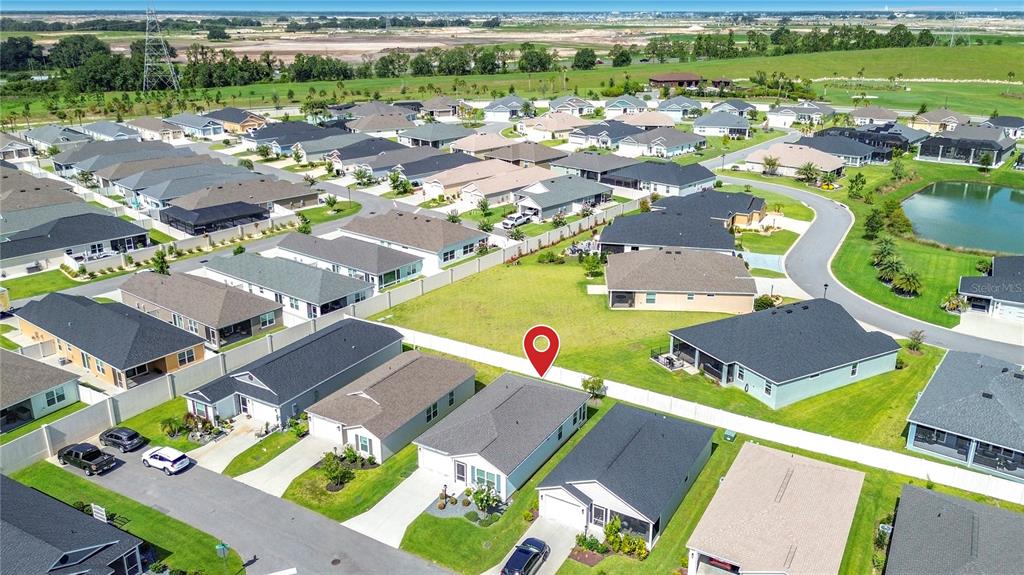 An aerial view shows a suburban neighborhood with single-family homes and a vacant lot — 6966 LISA LANE, THE VILLAGES, FL
