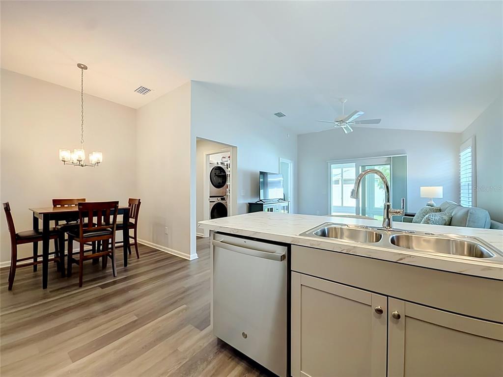 A kitchen island with a double sink overlooks a dining area and a living room — 6966 LISA LANE, THE VILLAGES, FL