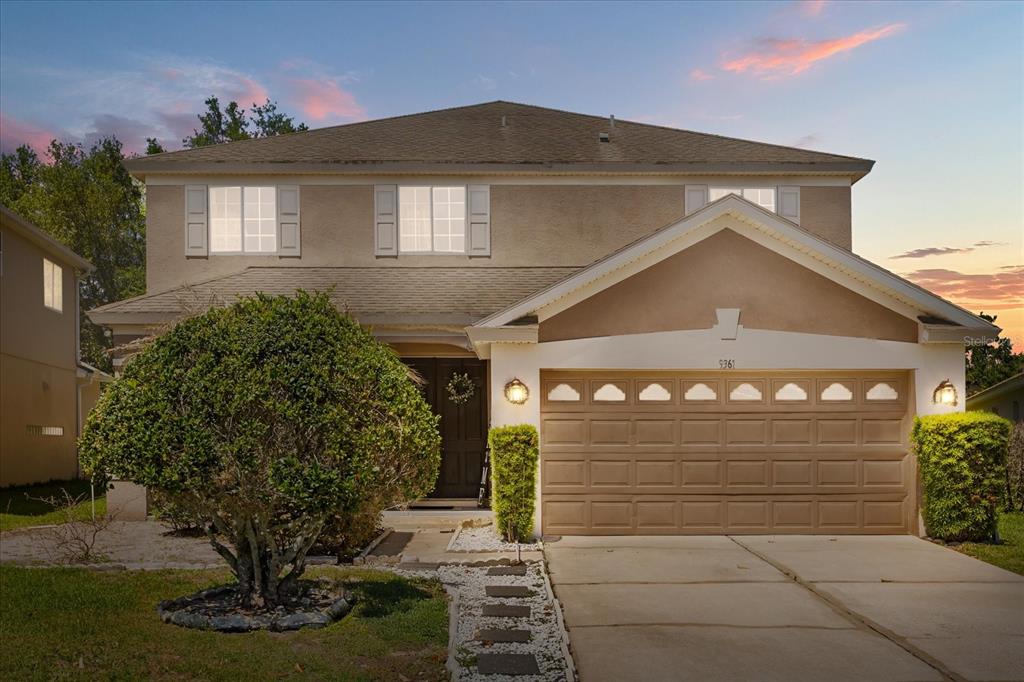 A two-story suburban house with a tan stucco exterior and an attached two-car garage — 9361 PECKY CYPRESS WAY, ORLANDO, FL