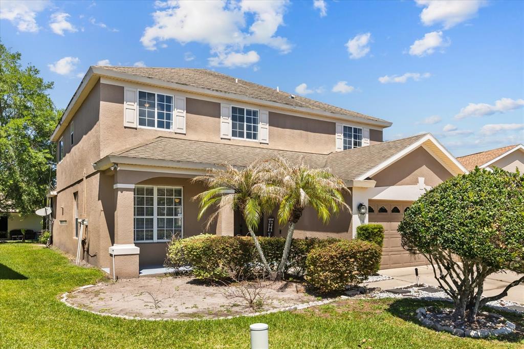 A two-story suburban house with a tan stucco exterior, a garage, and a front yard — 9361 PECKY CYPRESS WAY, ORLANDO, FL