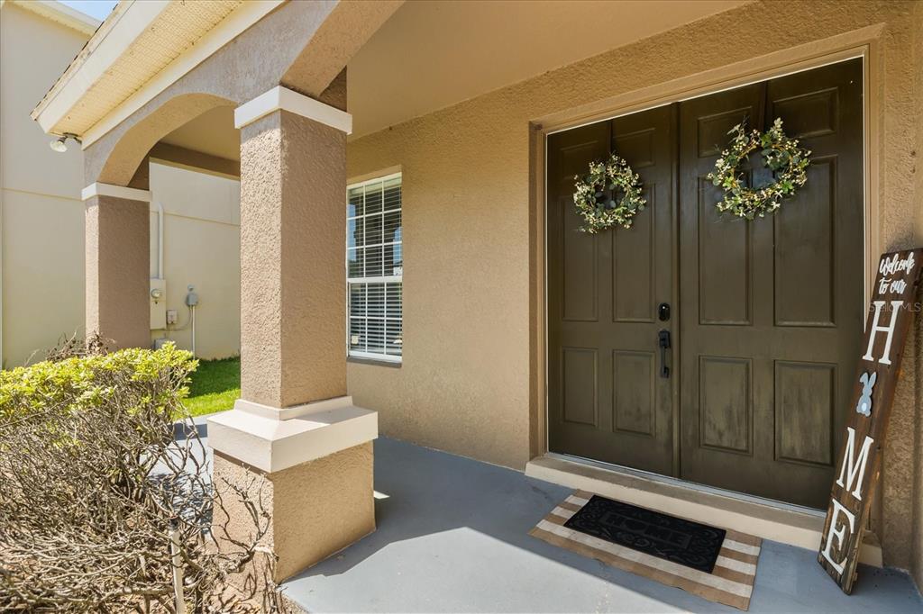 A covered front porch features a double door entrance with wreaths and a welcome sign — 9361 PECKY CYPRESS WAY, ORLANDO, FL