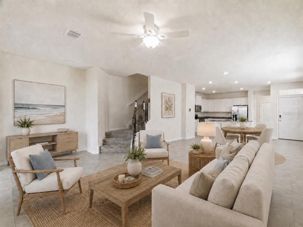 A living room with light tile floors, a beige sofa, armchairs, and an open kitchen — 108 REDBUD ROAD, PALM COAST, FL