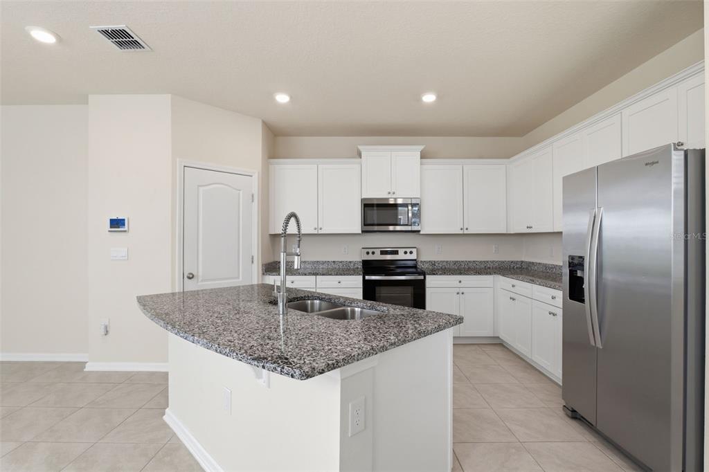 A kitchen with white cabinets, granite countertops, stainless steel appliances, and a central island — 108 REDBUD ROAD, PALM COAST, FL