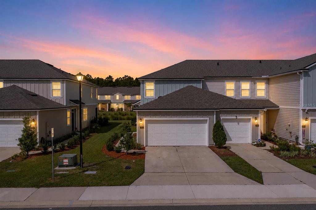 Exterior view of two-story townhomes with attached garages at sunset — 108 REDBUD ROAD, PALM COAST, FL