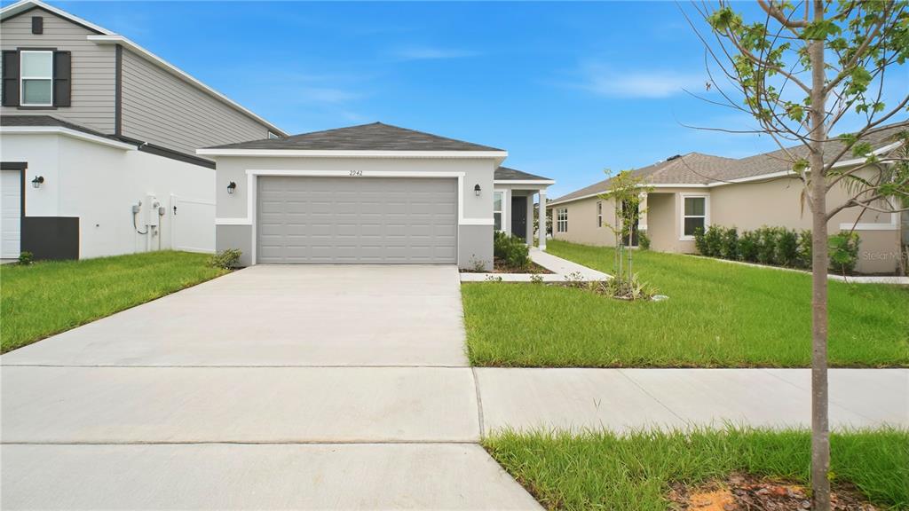 A single-story house with a gray garage, light siding, and a concrete driveway — 2942 LAVANDA DRIVE, HAINES CITY, FL