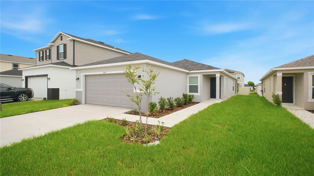 A single-story house with a gray garage, light-colored stucco exterior, and a manicured lawn — 2942 LAVANDA DRIVE, HAINES CITY, FL