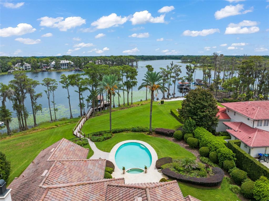 An aerial view shows a house with a tiled roof, a swimming pool, and a lake — 6055 LOUISE COVE DRIVE, WINDERMERE, FL