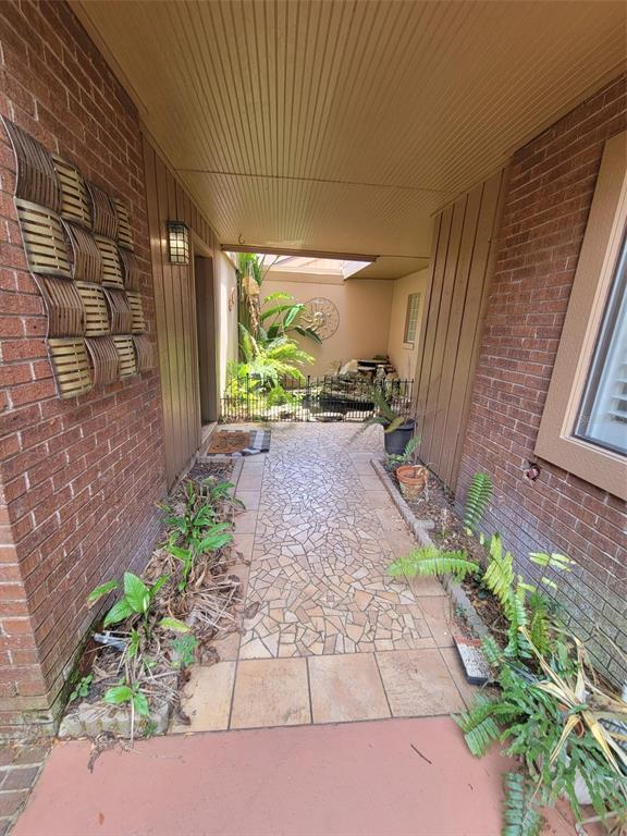 A covered brick entryway leads to a small courtyard featuring a pond and decorative wall art — 101 CEDAR POINT LANE, LONGWOOD, FL