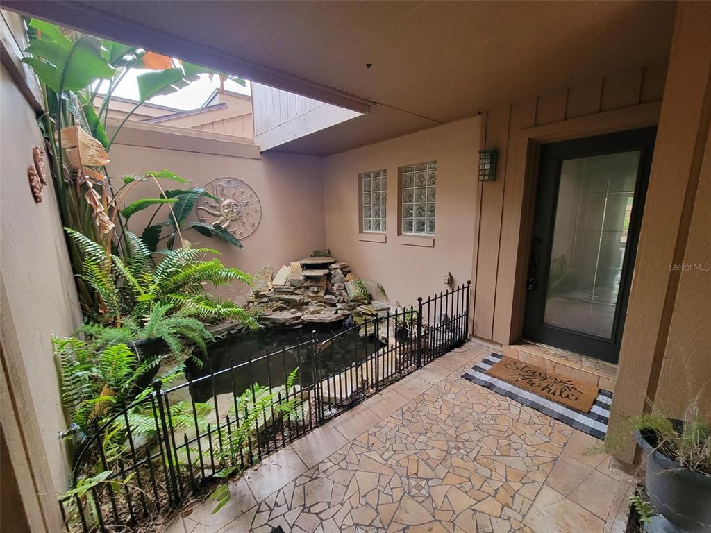 An outdoor courtyard features a stone waterfall, a small pond, and a tiled entryway — 101 CEDAR POINT LANE, LONGWOOD, FL
