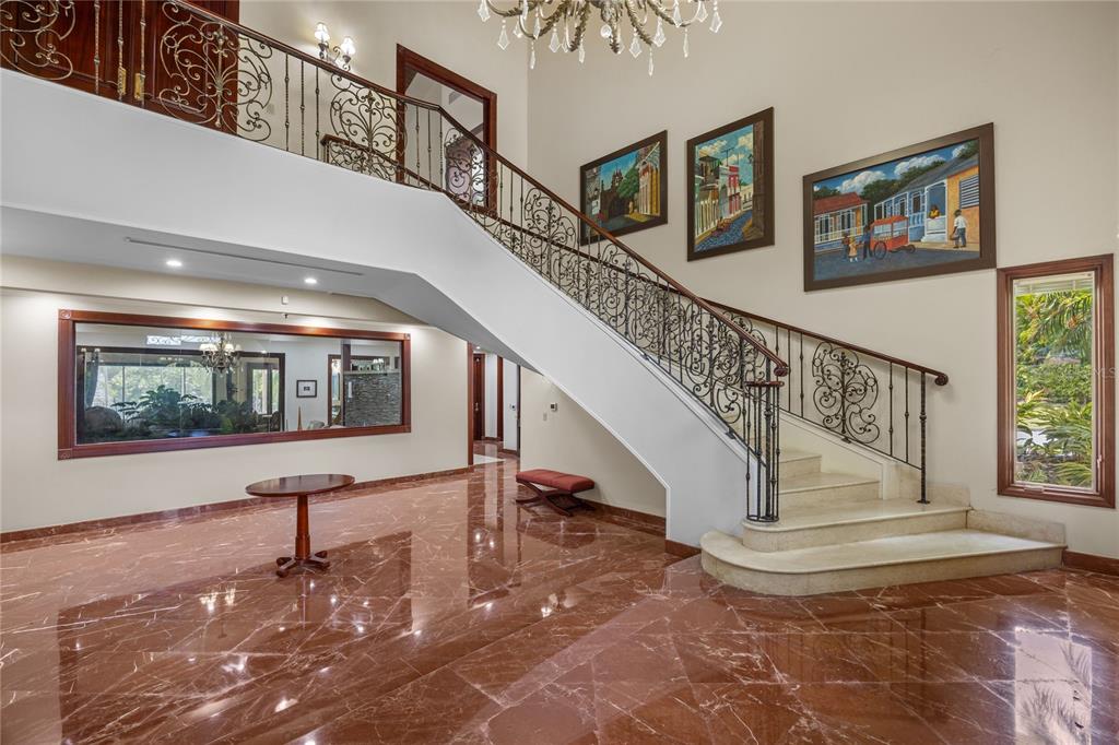 A grand foyer features a sweeping staircase with ornate iron railings and polished marble floors — 17 Calle Durazno URBANIZACION SAN PATRICIO, GUAYNABO, PR