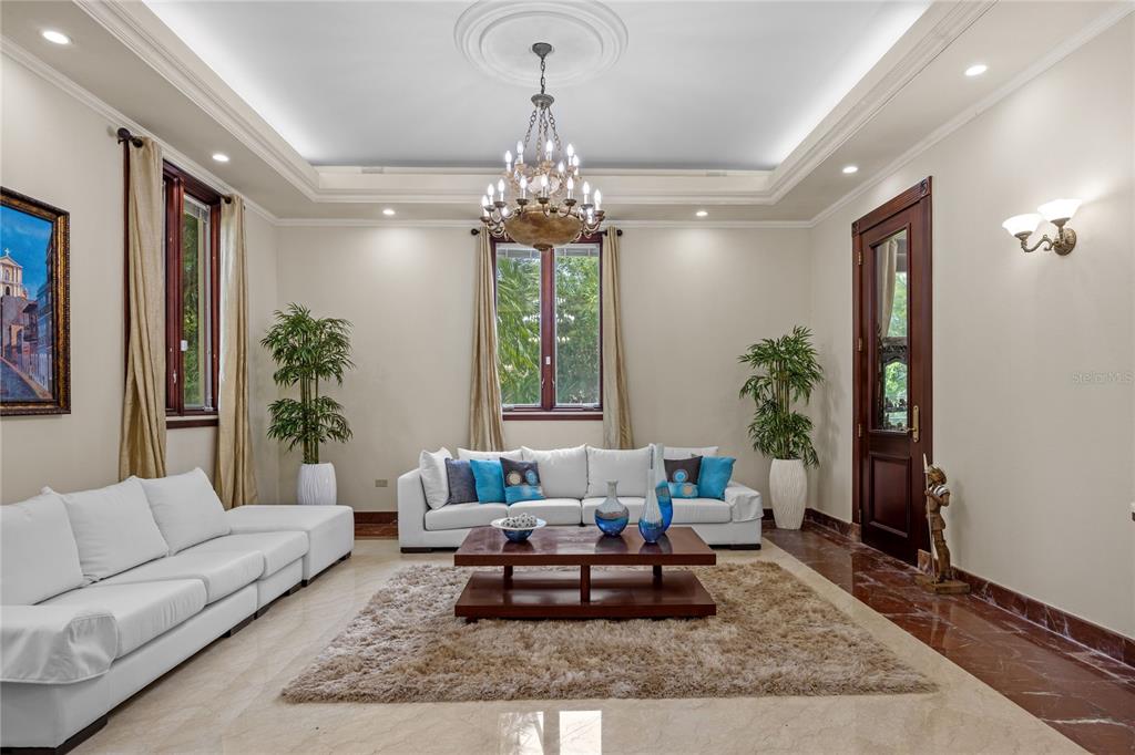 A living room features white sofas, a wooden coffee table, a chandelier, and marble flooring — 17 Calle Durazno URBANIZACION SAN PATRICIO, GUAYNABO, PR