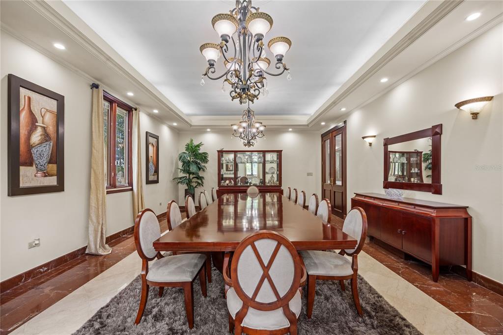 A formal dining room features a long wooden table, upholstered chairs, and two ornate chandeliers — 17 Calle Durazno URBANIZACION SAN PATRICIO, GUAYNABO, PR