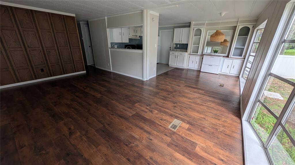 An open-concept living area features wood-look flooring, a paneled accent wall, and a kitchen pass-through — 11716 E U.S. HIGHWAY 92, SEFFNER, FL